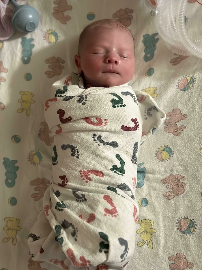 Newborn baby wrapped in a footprint blanket sleeping peacefully, capturing the essence of what it means to be a dad.