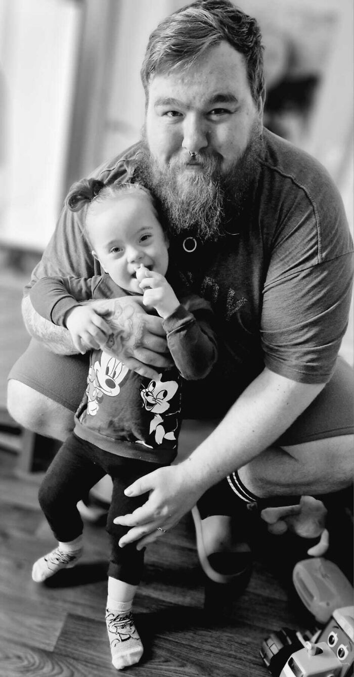 Father happily hugging his toddler daughter indoors, capturing the wholesome and funny moments that define being a dad