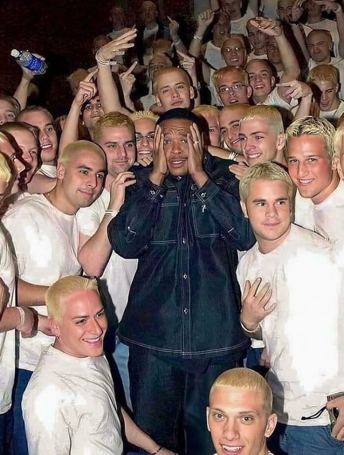 Group of people surrounding a man, capturing a funny moment that makes you go 'hmmm'.