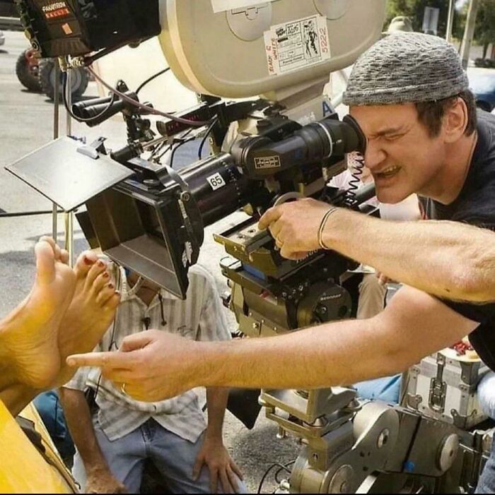 Film director focused on a camera, capturing a close-up of a person's foot, provoking a 'hmmm' moment on set.