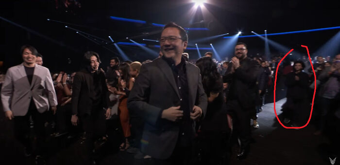 People in formal attire at an event with one person circled, highlighting someone acting like they belong.