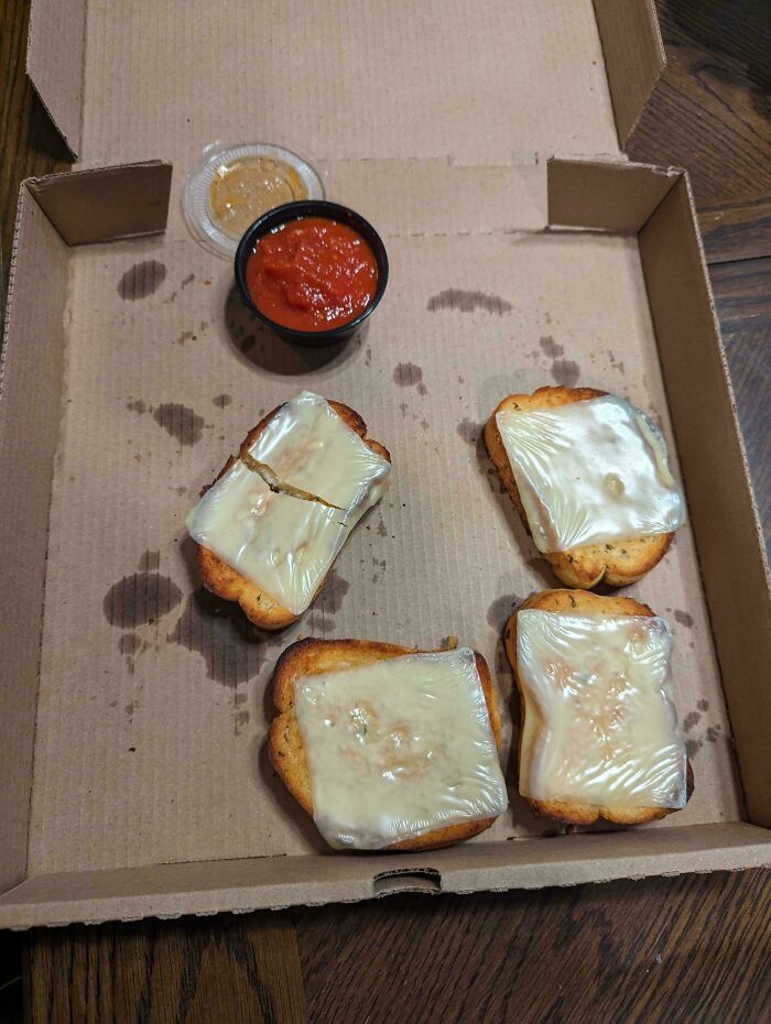 Cheese toast with plastic wrap served in a box; an example of weird food presentation.