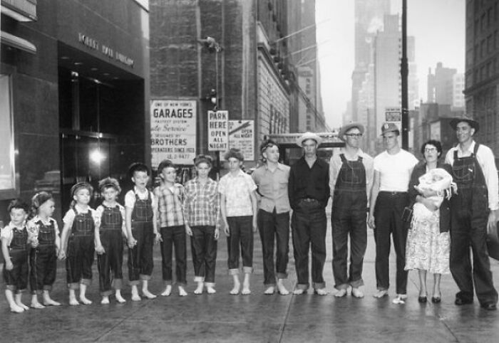 A group of people of varying heights lined up on a city sidewalk showcasing a wild coincidence captured in a photo.