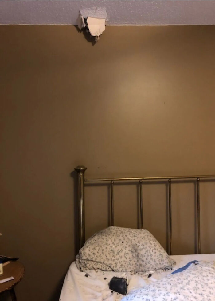Bedroom with a bed under a ceiling hole where debris landed, showing wild coincidences captured in photos.