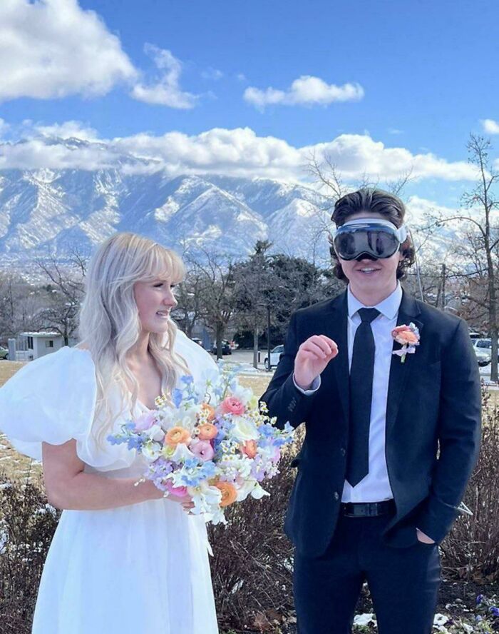 A groom in goggles at a wedding with a scenic mountain backdrop, bride holding bouquet, showcasing unusual wedding moments.