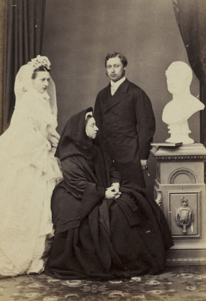 Victorian wedding photo with bride, groom, and seated woman beside a bust, exemplifying unusual weddings shared online.