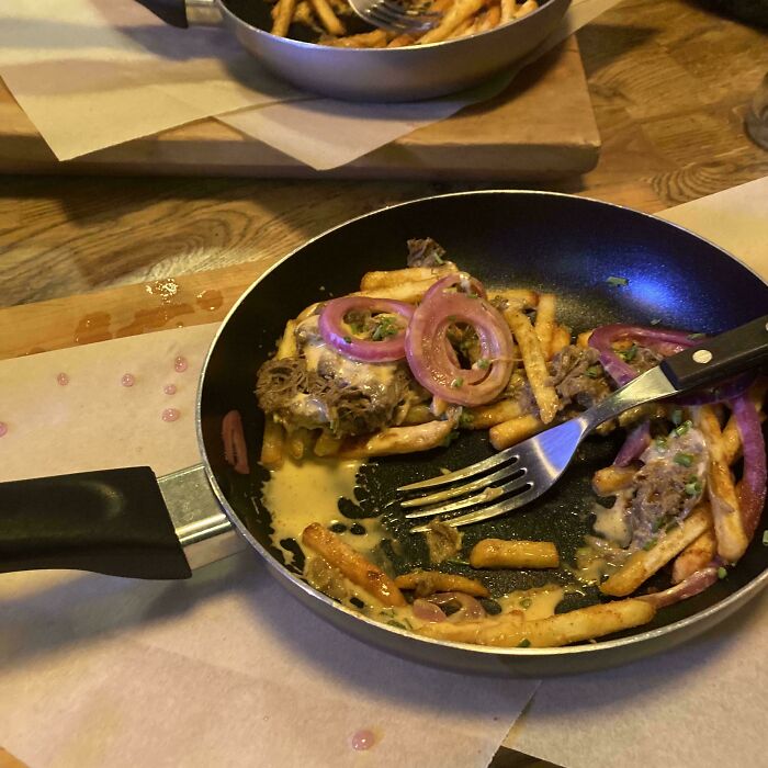 Fries and toppings served in a small frying pan, showcasing one of the most ridiculous ways food is served in restaurants.