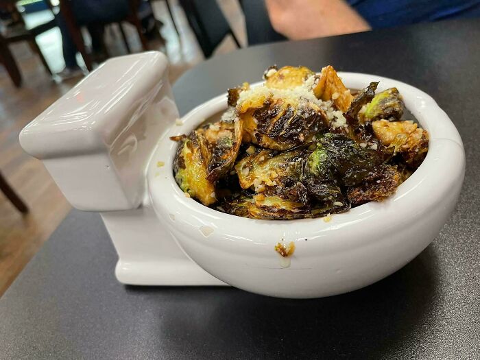 Roasted Brussels sprouts served in a toilet-shaped dish as a ridiculous food presentation in a restaurant.