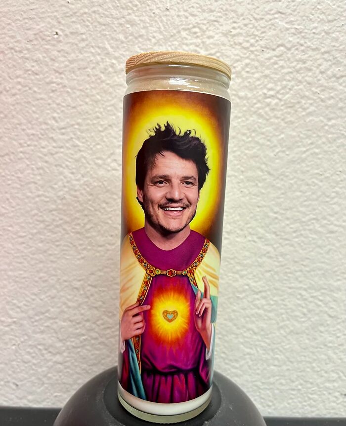 Candle with a humorous design featuring a smiling man’s face on a religious figure’s body, a quirky Amazon find.