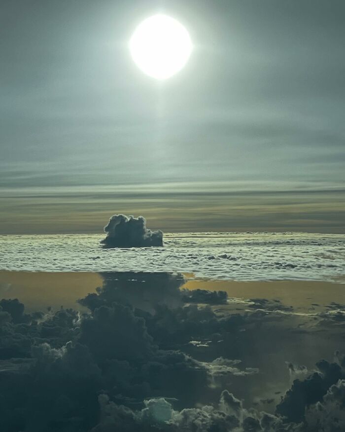 Aerial photo showing the sun above a layered cloudscape with dramatic light and shadow captured by a pilot.