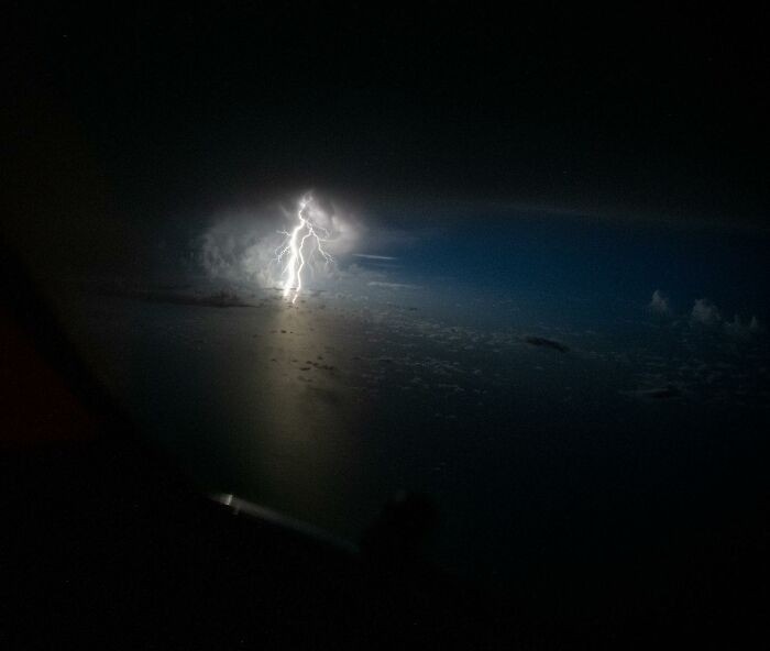 Aerial photo of a lightning strike over ocean waters captured by a pilot during a nighttime flight.