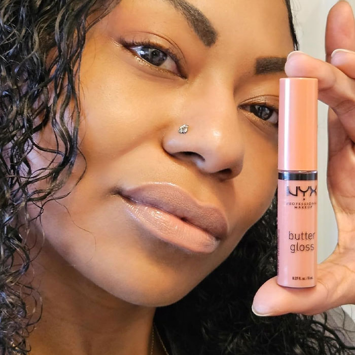Woman holding NYX Butter Gloss, a cheap and cheerful Mother's Day gift.