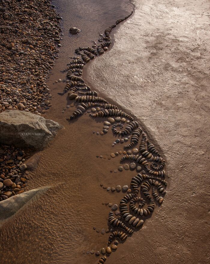 Intricate land art piece made with natural materials arranged along a riverbank showcasing patience and creativity.