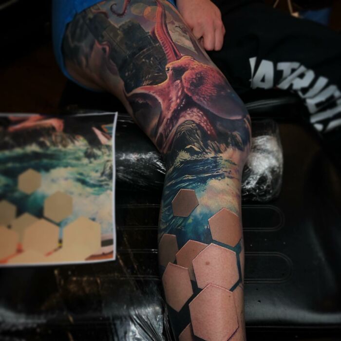 Tattoos capturing a world within skin, featuring a realistic octopus and ocean scene on a person's leg.