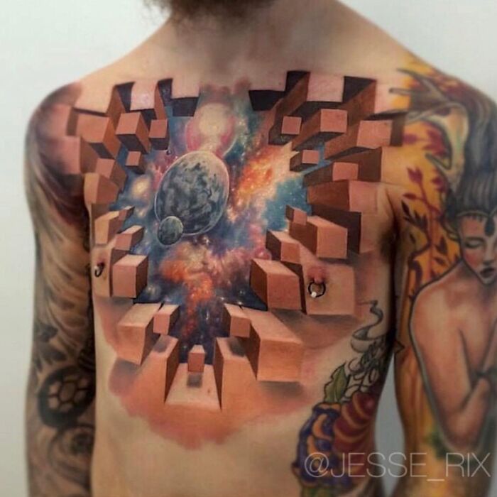 Mind-bending tattoo on chest, featuring cosmic scene with planets and cubes, creating a 3D effect on the skin.
