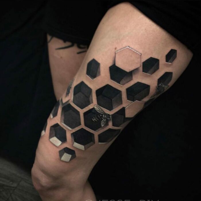 Hexagonal tattoo design on arm, creating a 3D illusion with black and white patterns, capturing a world within the skin.