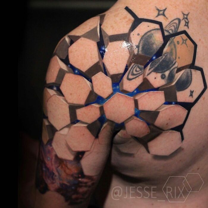 Mind-bending tattoo with hexagonal shapes and cosmic elements on a shoulder, creating a 3D effect.