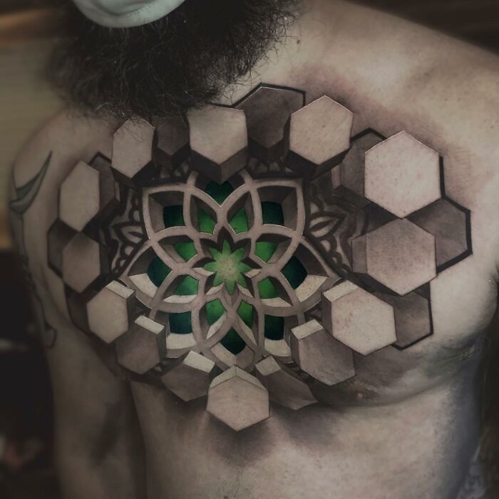 3D geometric tattoo with hexagons and a green mandala on a man's chest, showcasing intricate skin art design.