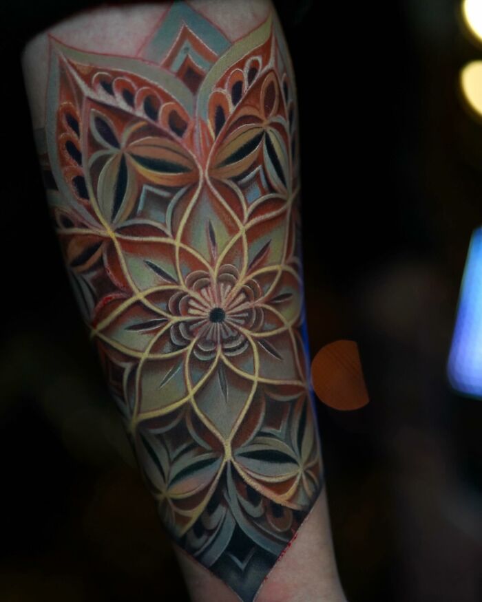 Intricate geometric tattoo on forearm, featuring layered patterns and earthy tones, showcasing world within the skin artistry.