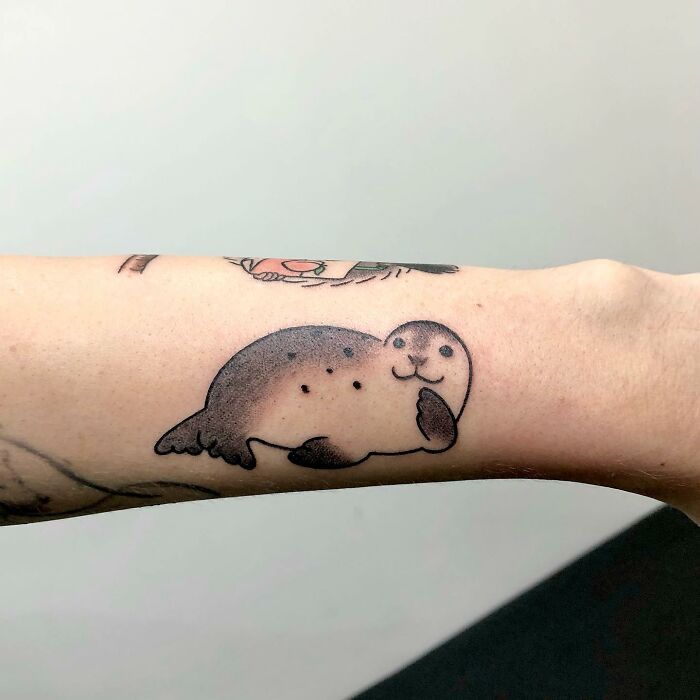 Seal tattoo with charming details on a forearm by tattoo artist Buoy.