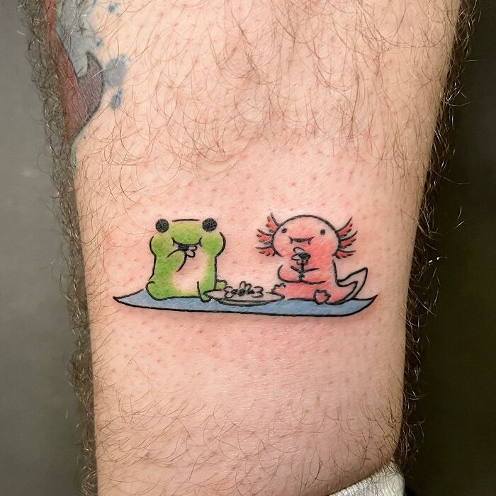 Charming tattoo of a cute frog and axolotl eating snacks, designed by Buoy.