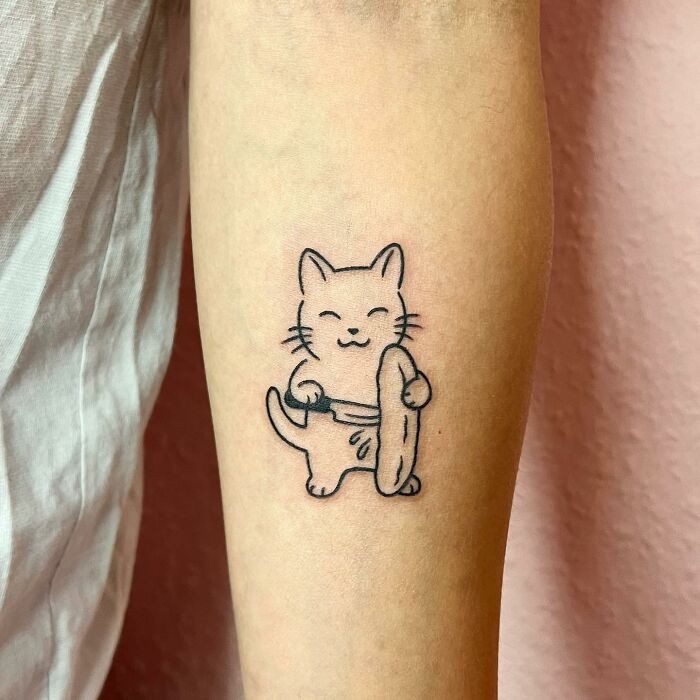 Charming tattoo of a cute cat with a sushi roll by Buoy, on a person's arm.