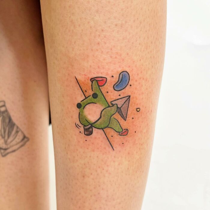 Cute green creature tattoo by Buoy on forearm, featuring a playful abstract design.