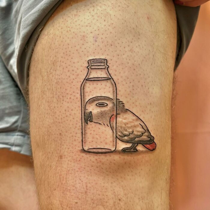 Cute parrot tattoo by Buoy inside a bottle on leg, showcasing minimalist and charming design.