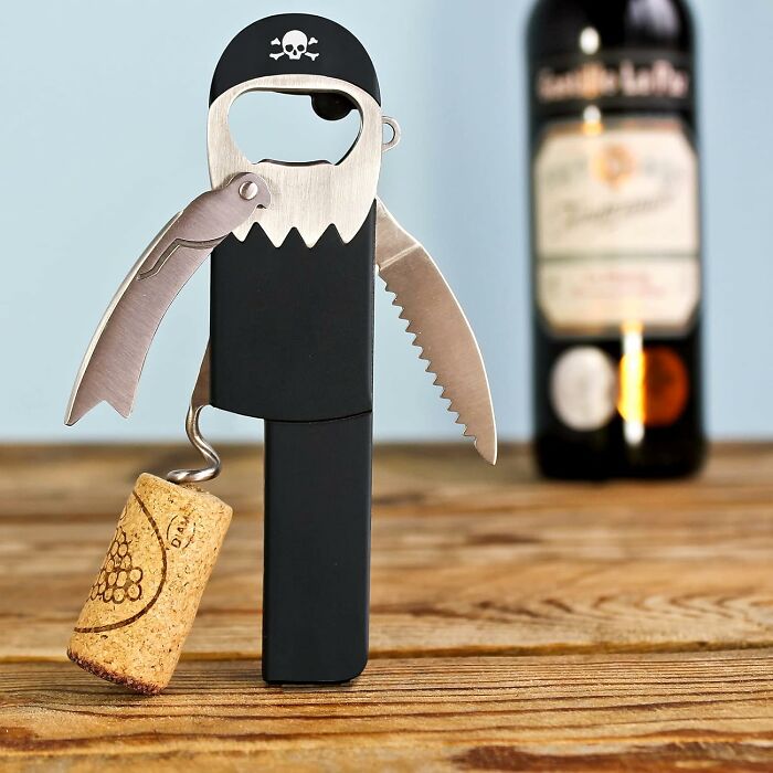 Pirate-themed kitchen multitool with corkscrew and bottle opener on wooden table.