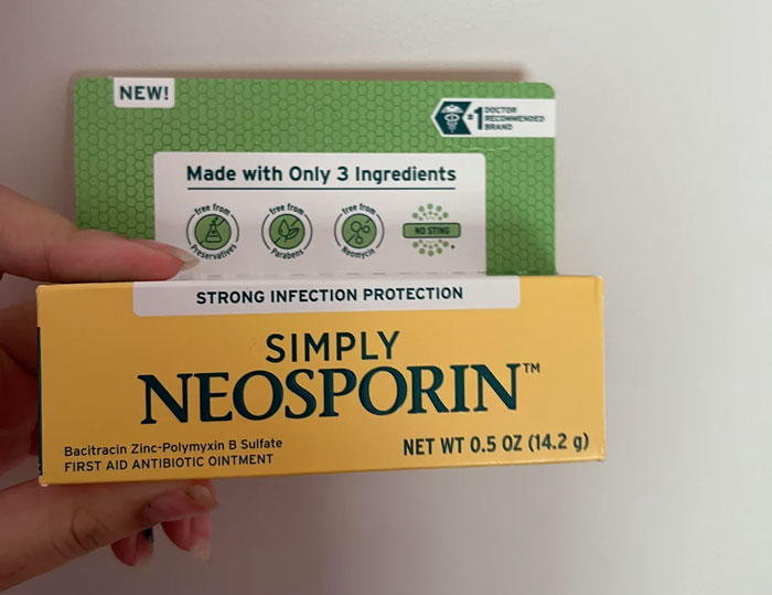 Neosporin antibiotic ointment box held in hand, highlighting infection protection and simple ingredients.