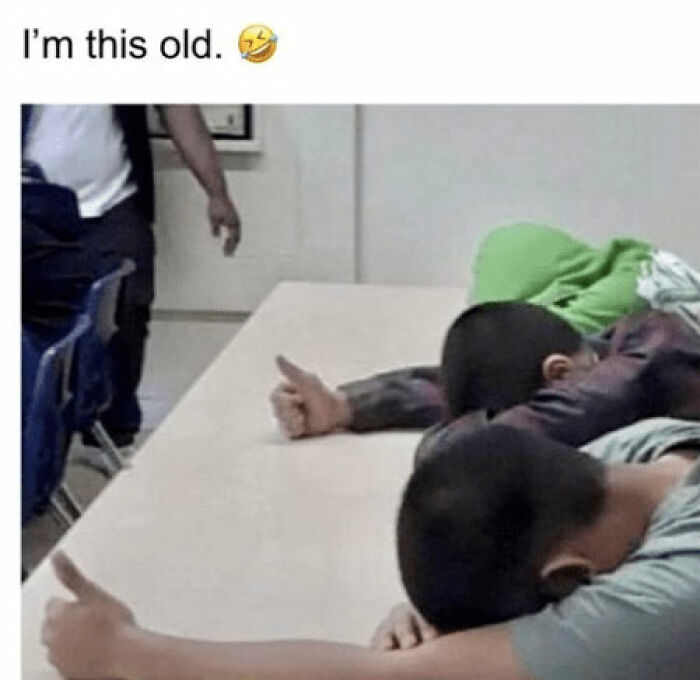 Two people at a table with heads down and thumbs up, referencing a funny '80s meme.