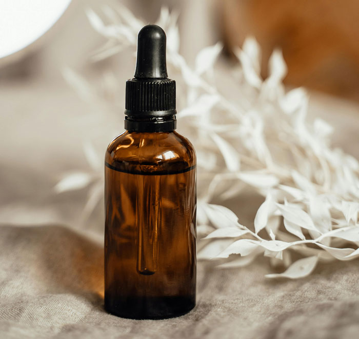 Amber dropper bottle on a fabric surface, suggesting alternative cleaning for dog teeth without brushing.