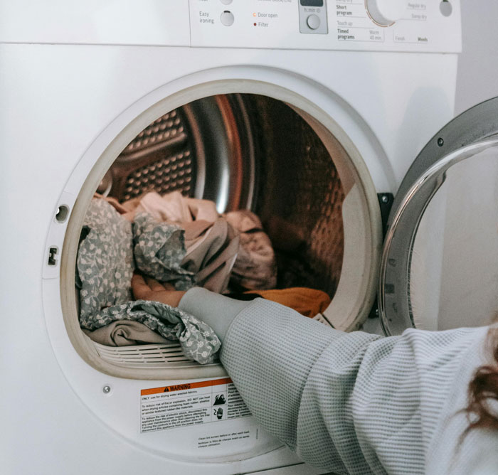 Person removing pet hair from clothes in dryer. - 2