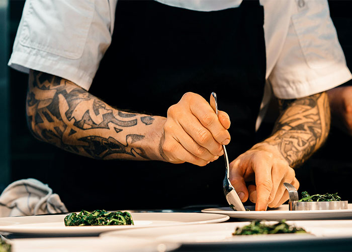 Tattooed machinist's hands preparing food in a kitchen setting. - 14