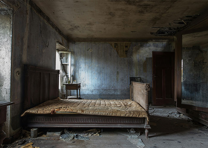 Abandoned bedroom with a decayed mattress and peeling walls, showing shocking living conditions and neglect.