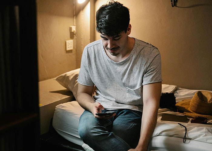 Young man looking shocked while sitting on a bed, illustrating moments people were shocked by how others live.