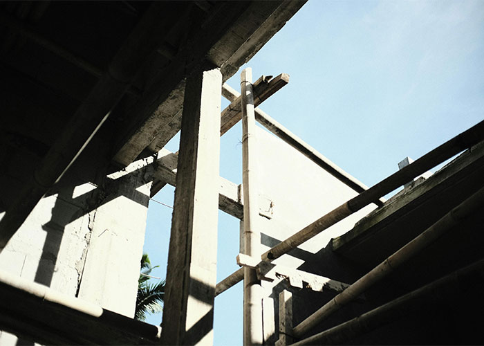 View of a partially built structure with wooden beams and concrete walls under bright sky showing shocking living conditions.