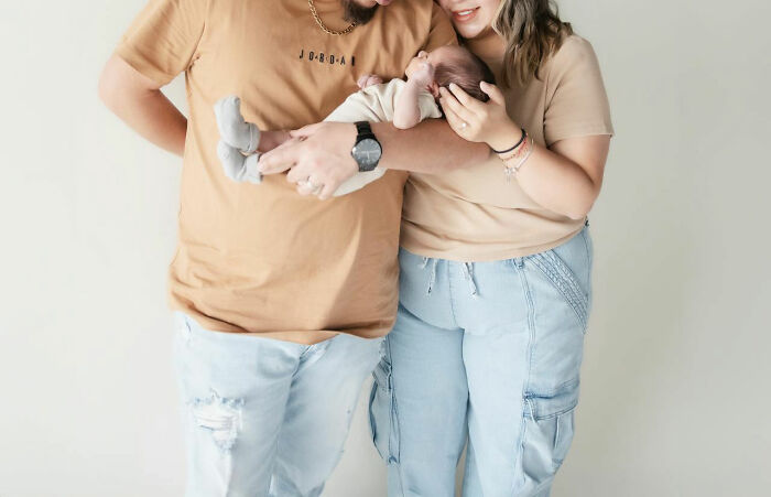 Couple in matching outfits lovingly hold their baby, highlighting unique baby names trend. - 16