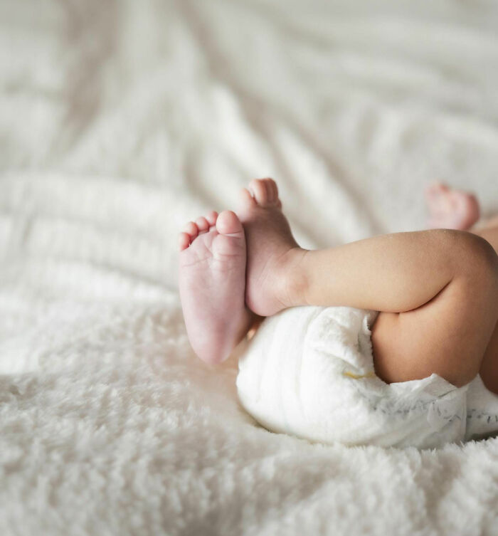 Baby lying on soft blanket, wearing a diaper, highlighting the humorous aspect of unique baby names. - 20