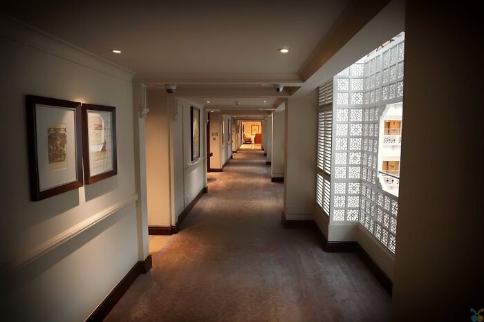 Interior view of a luxury resort hallway with framed pictures and decorative window panels, showing employees' secret insights.
