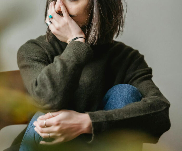 Person in a deep green sweater sitting pensively, highlighting hilarious baby names. - 12