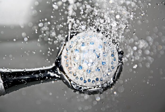 Close-up of water spraying from a luxury resort shower head revealing details of resort employees' hidden secrets.