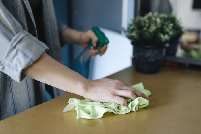 Employee cleaning a luxury resort surface with a spray bottle and cloth, revealing behind-the-scenes secrets and service details.