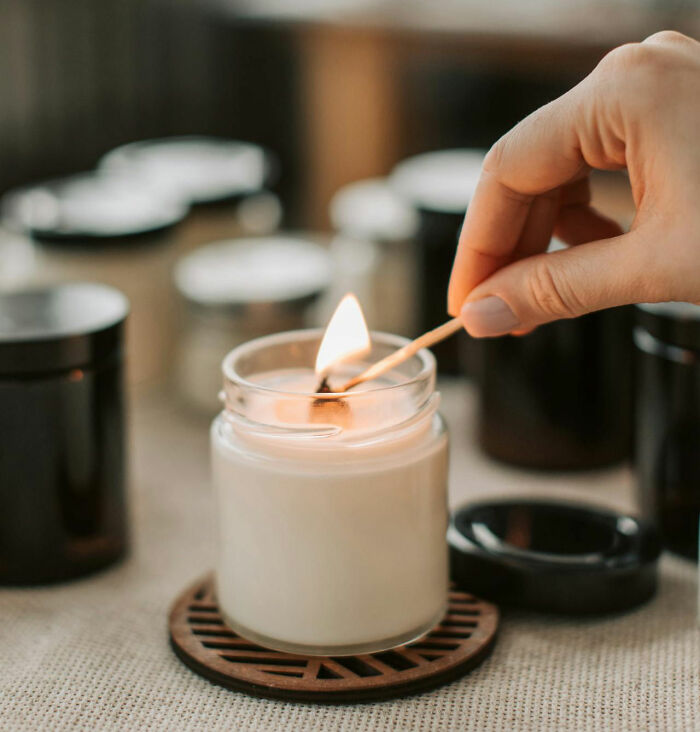 Hand lighting a scented candle with a matchstick in a cozy setting. - 10
