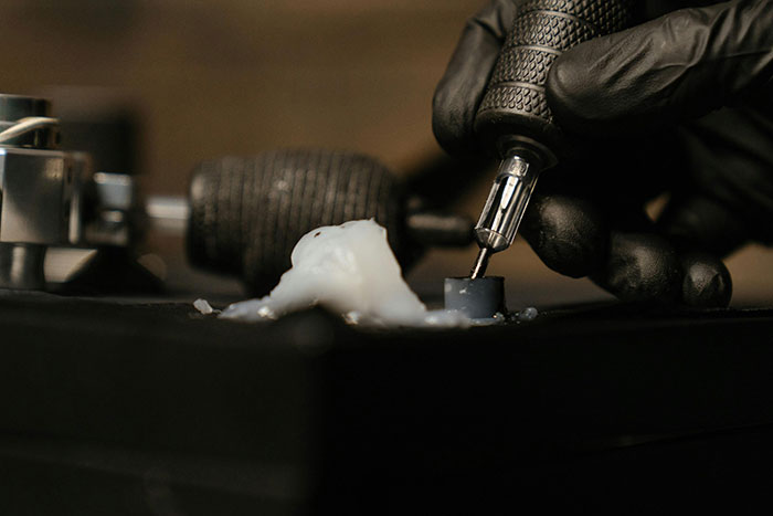 Tattoo artist with gloves holding tattoo machine, preparing for work on memorial tattoo. Tattoo artist with gloves holding tattoo machine, preparing for work on memorial tattoo.