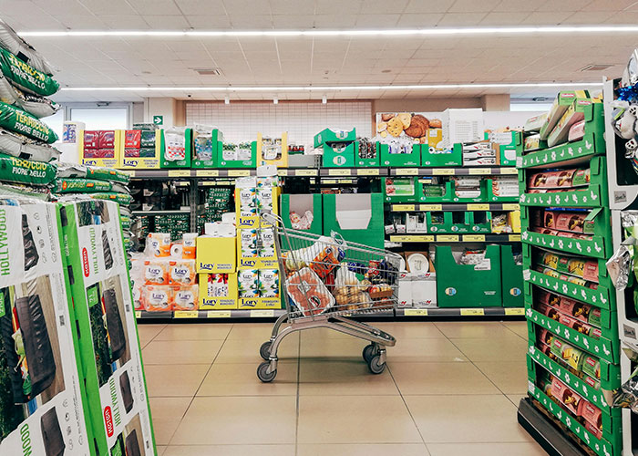 Shopping cart in a store aisle filled with various packaged goods, illustrating wildest things the rich can purchase.