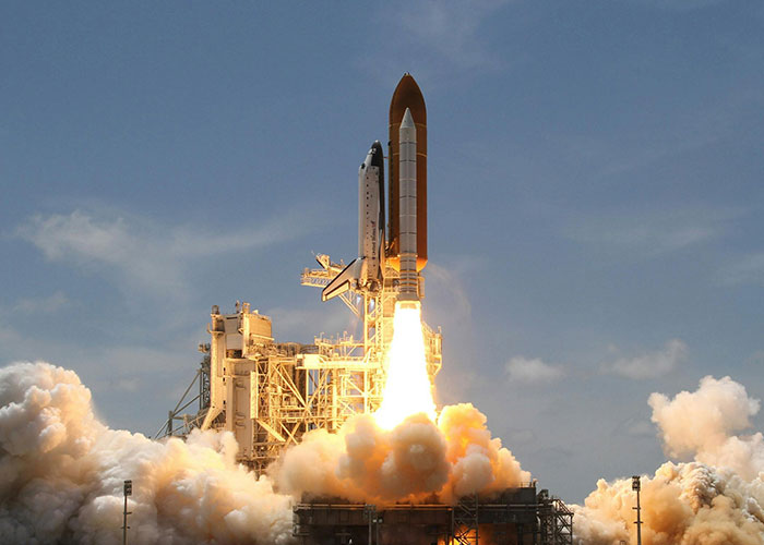 Space shuttle launching into the sky with flames and smoke, showcasing one of the wildest things the rich can purchase.