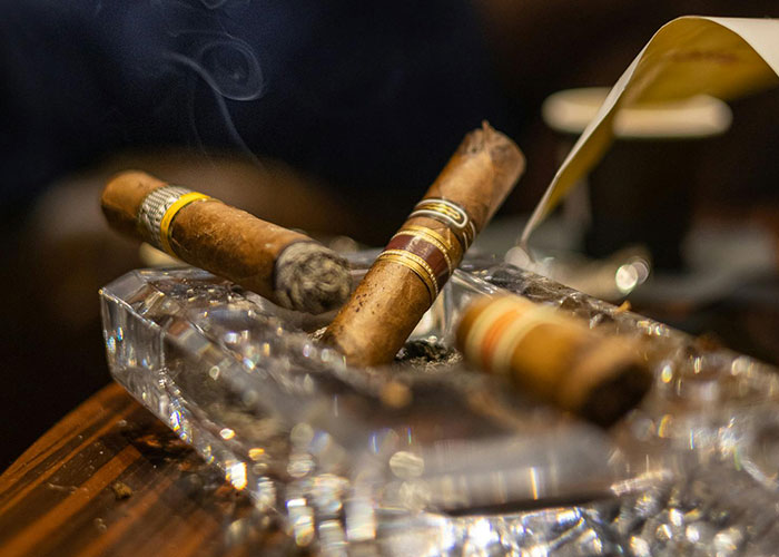 Close-up of luxury cigars burning in a crystal ashtray, showcasing wildest things the rich can purchase.