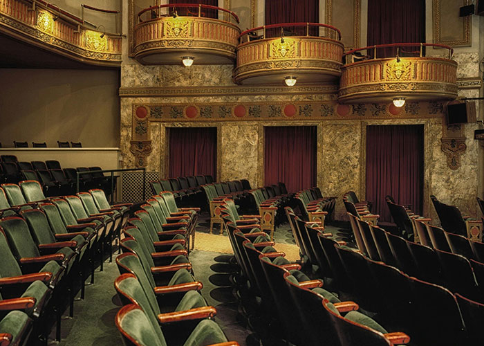 Ornate vintage theater interior with plush seats and private balconies, showcasing luxurious purchases the rich can make.