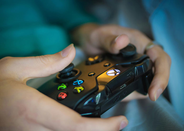 Close-up of hands holding a black gaming controller, illustrating wildest things the rich can purchase.